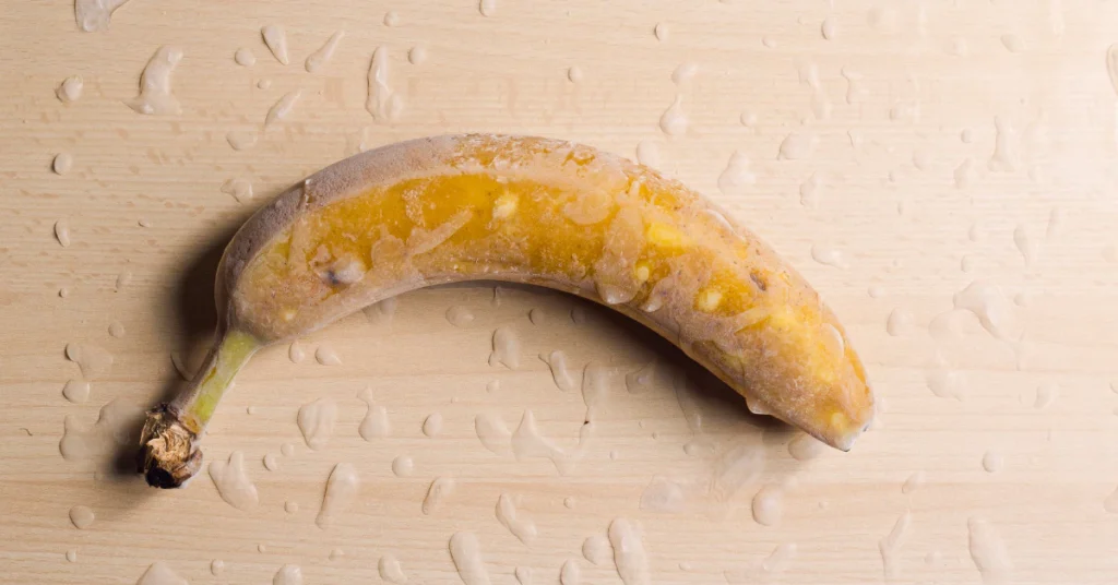 Whole ripe banana with its peel on a light beige background