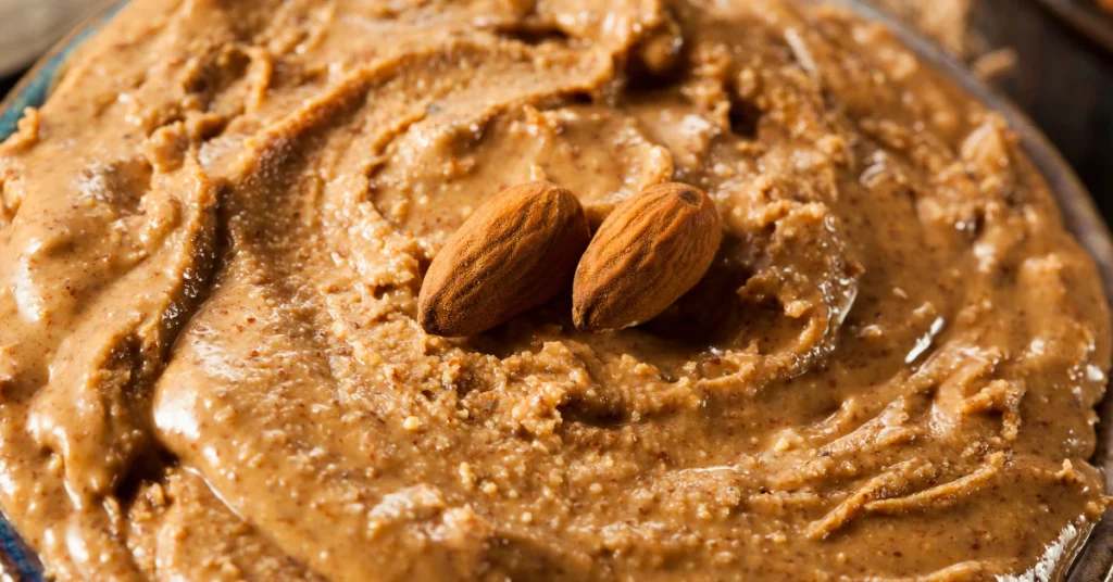 Jar of creamy almond butter topped with whole almonds