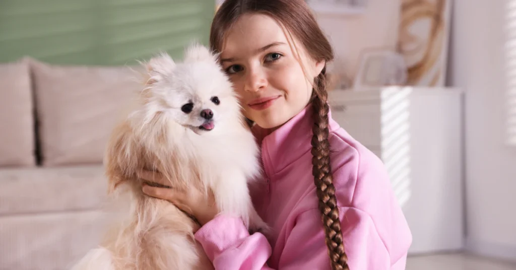 Woman hugging a small fluffy dog indoors
