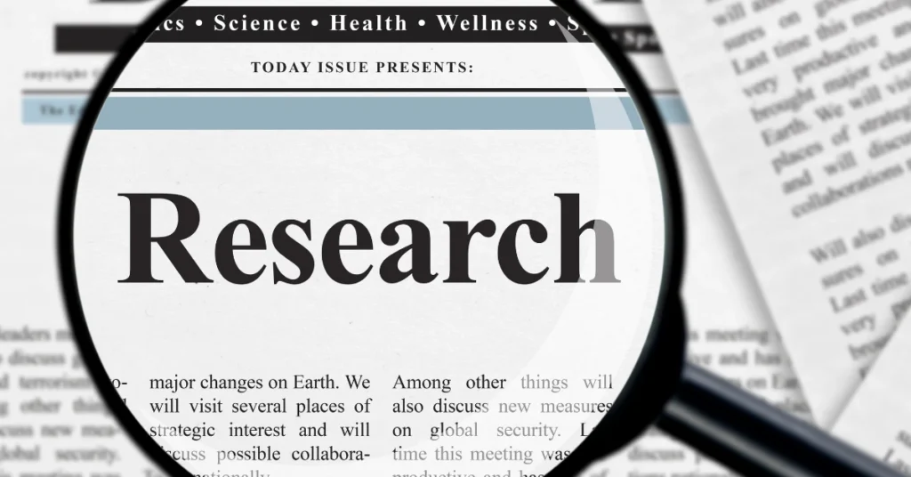 Magnifying glass over the word research in a newspaper
