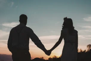 Silhouette of a couple holding hands while standing together at sunset