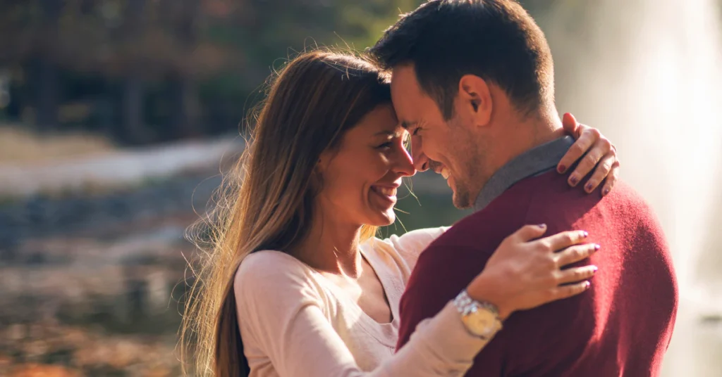 Smiling couple embracing each other closely near the water